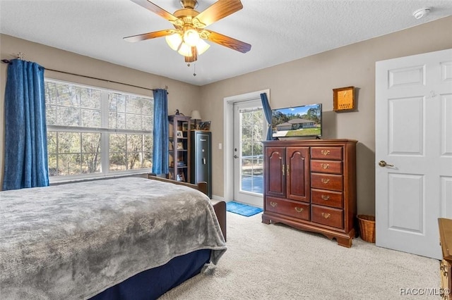 bedroom with light carpet, access to outside, a textured ceiling, and a ceiling fan