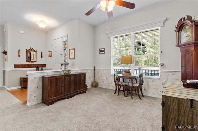 interior space featuring wainscoting, a ceiling fan, and light colored carpet