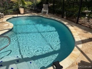 outdoor pool featuring glass enclosure and a patio area