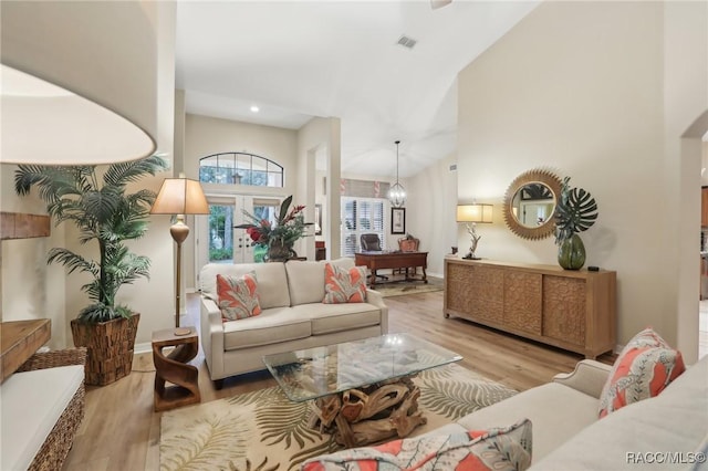 living area featuring visible vents, high vaulted ceiling, an inviting chandelier, and wood finished floors