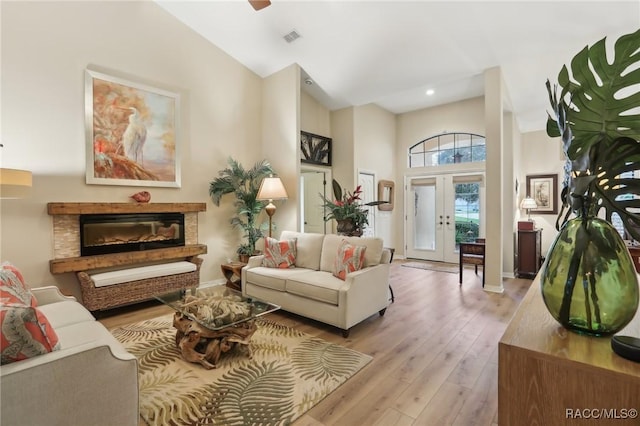 living area with visible vents, a glass covered fireplace, french doors, wood-type flooring, and baseboards