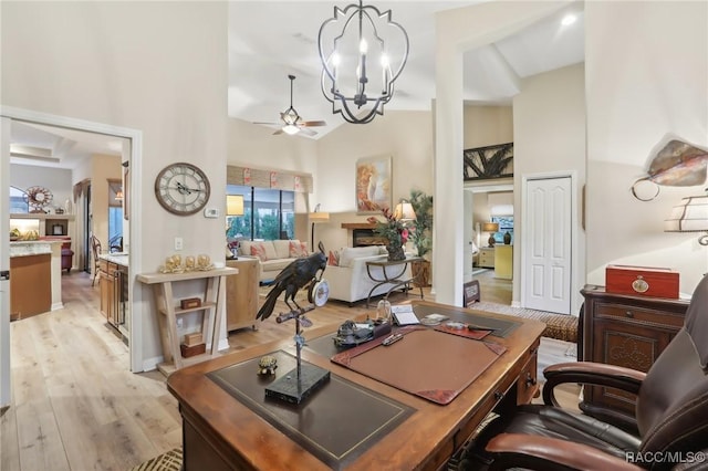 office with light wood finished floors, high vaulted ceiling, and ceiling fan with notable chandelier