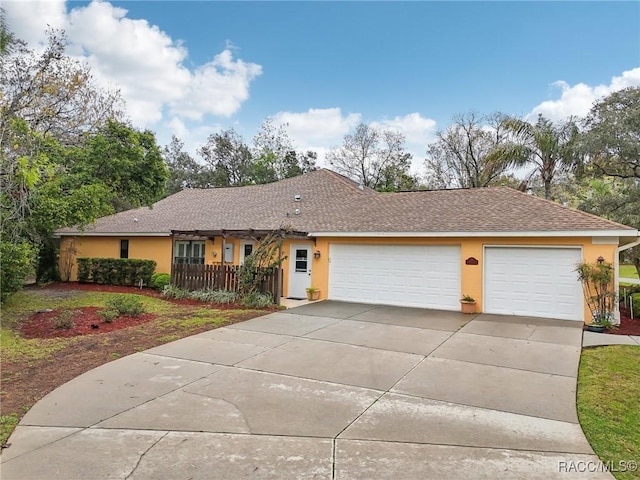 ranch-style house featuring concrete driveway, a garage, roof with shingles, and stucco siding