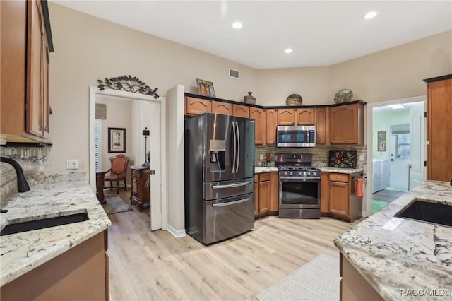 kitchen with visible vents, light stone countertops, decorative backsplash, appliances with stainless steel finishes, and a sink