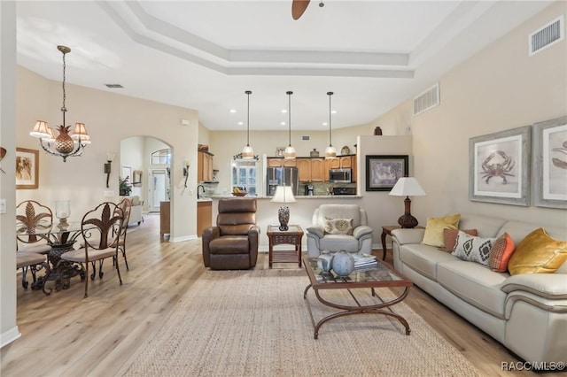 living area with light wood-style floors, arched walkways, and visible vents