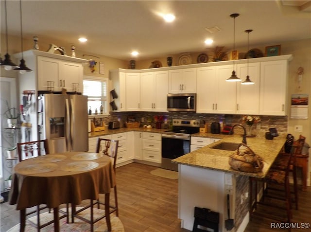 kitchen with white cabinetry, sink, hanging light fixtures, kitchen peninsula, and appliances with stainless steel finishes