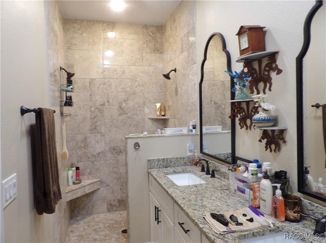 bathroom with tiled shower and vanity