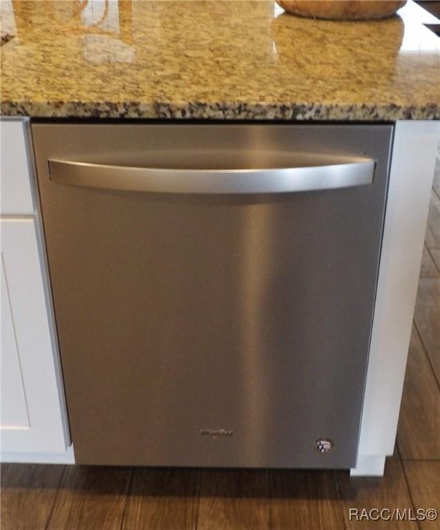 room details featuring white cabinets, light stone counters, and stainless steel dishwasher