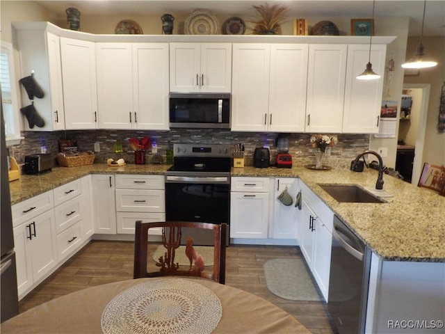 kitchen with hanging light fixtures, white cabinets, stainless steel appliances, and sink