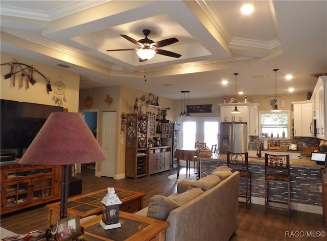 living room featuring ceiling fan, french doors, dark wood-type flooring, a raised ceiling, and ornamental molding