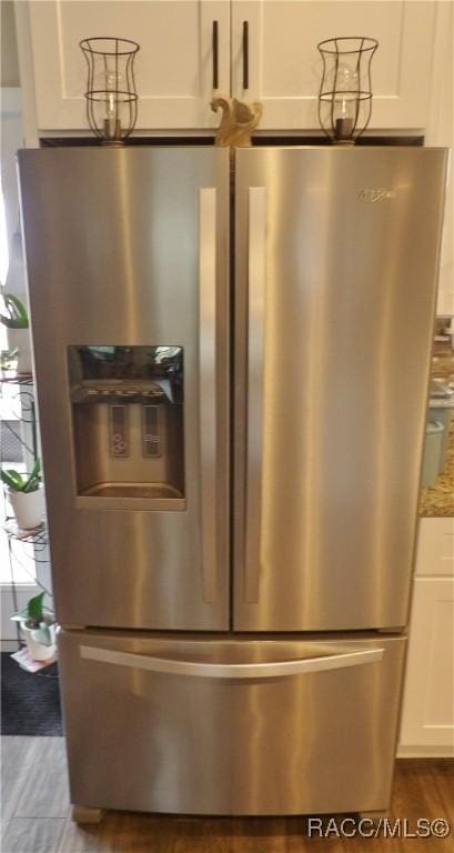 room details featuring hardwood / wood-style floors, stainless steel fridge, white cabinetry, and light stone counters