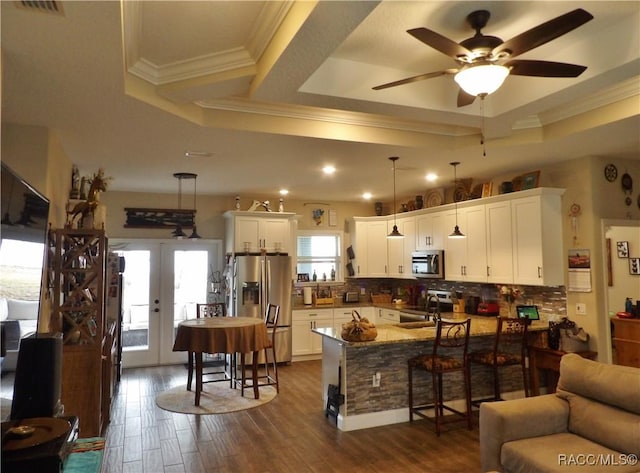 kitchen with a raised ceiling, white cabinetry, hanging light fixtures, and appliances with stainless steel finishes