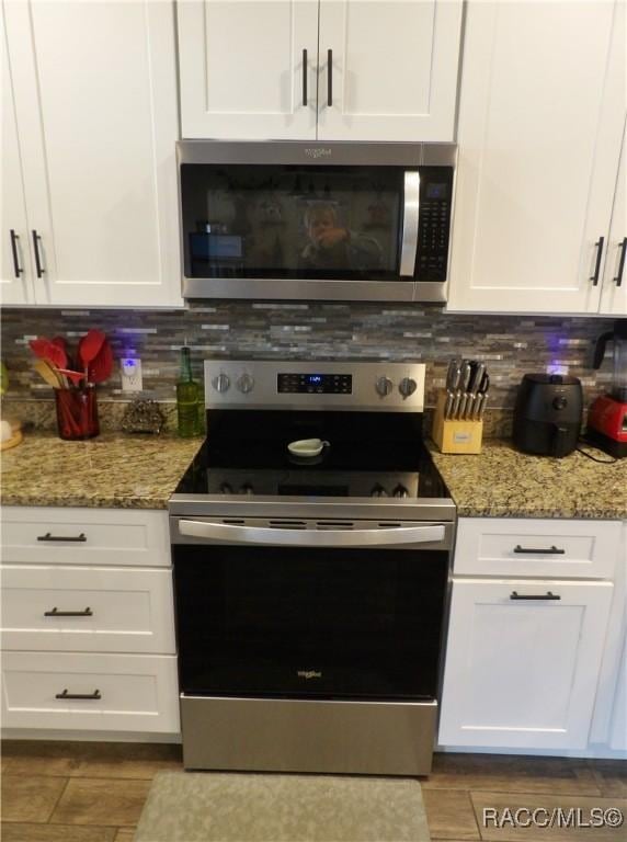 kitchen with white cabinets, decorative backsplash, stainless steel appliances, and light stone countertops