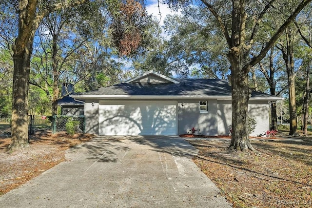 view of front facade with driveway, an attached garage, and fence