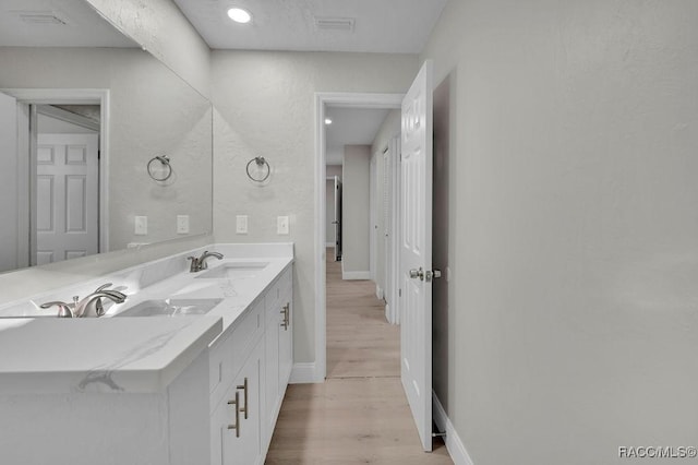 bathroom with double vanity, a sink, baseboards, and wood finished floors