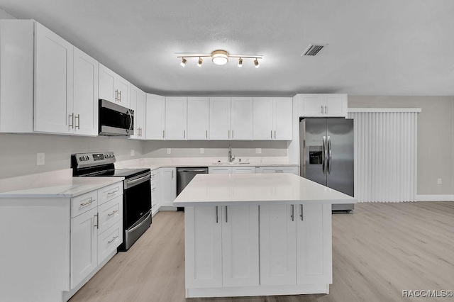 kitchen with light wood finished floors, visible vents, appliances with stainless steel finishes, light countertops, and a sink