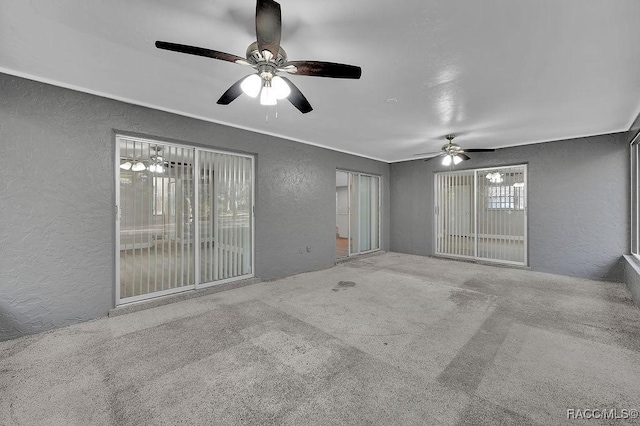 empty room featuring ceiling fan, a textured wall, and carpet