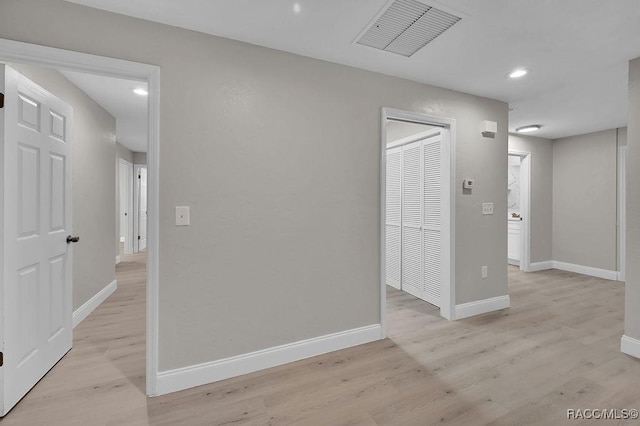 empty room featuring light wood-type flooring, baseboards, visible vents, and recessed lighting