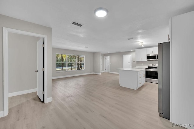 kitchen featuring a center island, light countertops, appliances with stainless steel finishes, open floor plan, and white cabinets