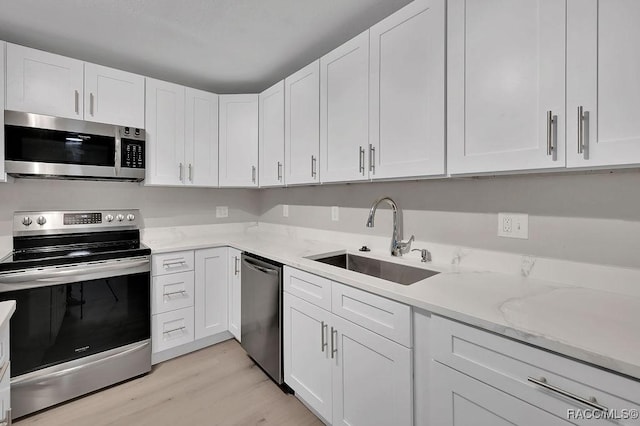 kitchen with stainless steel appliances, white cabinetry, and a sink