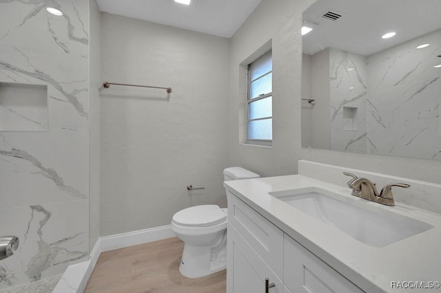 full bath featuring toilet, wood finished floors, visible vents, vanity, and baseboards