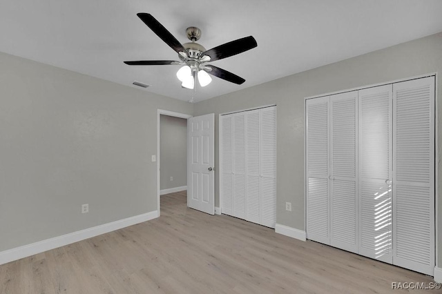 unfurnished bedroom with light wood finished floors, multiple closets, visible vents, ceiling fan, and baseboards