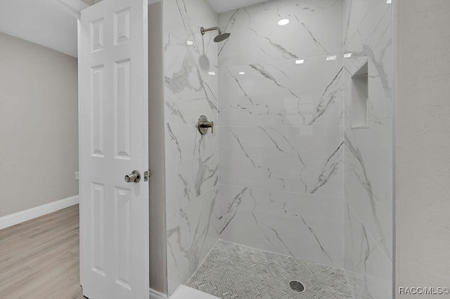 bathroom with a marble finish shower, baseboards, and wood finished floors