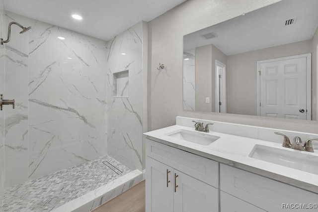 bathroom with visible vents, a sink, and a marble finish shower