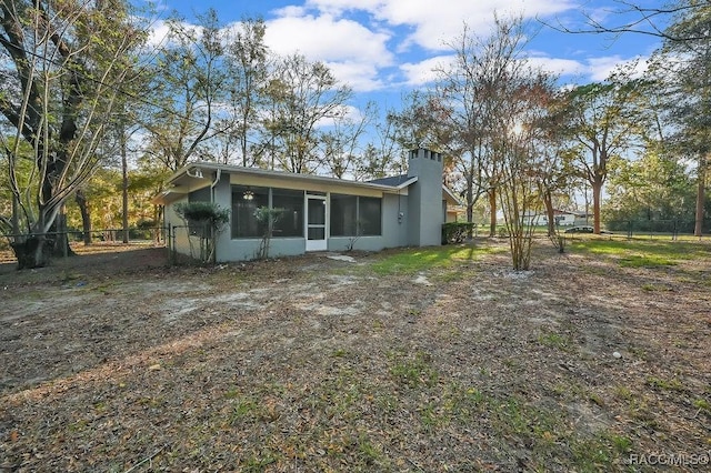 rear view of property with a sunroom, fence, and a chimney