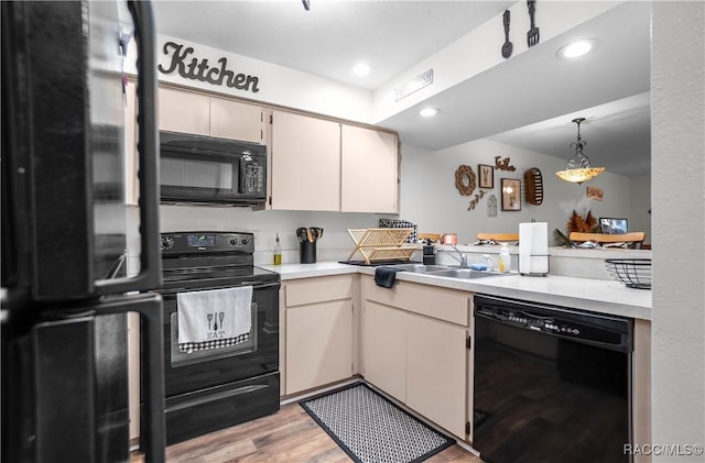 kitchen featuring sink, cream cabinets, black appliances, decorative light fixtures, and light wood-type flooring