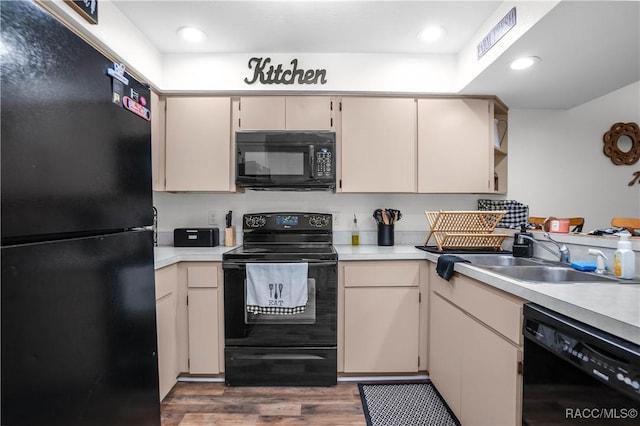 kitchen featuring sink, dark wood-type flooring, cream cabinetry, and black appliances