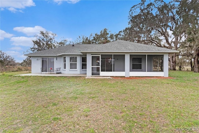 back of property with roof with shingles, stucco siding, a yard, a sunroom, and a patio area