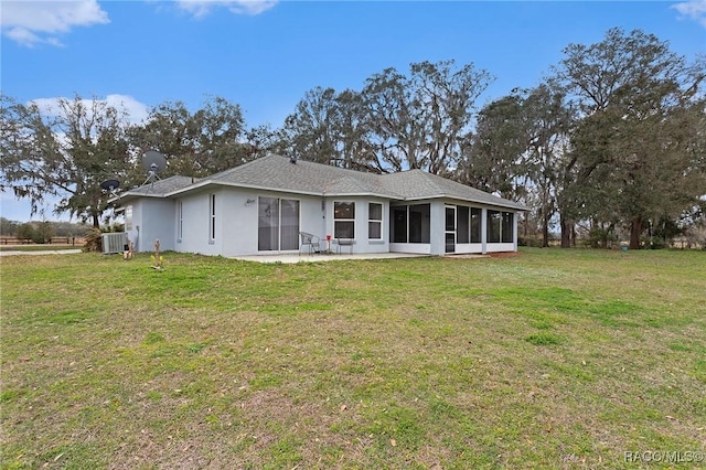 back of property featuring stucco siding, a lawn, a patio, central AC, and a sunroom