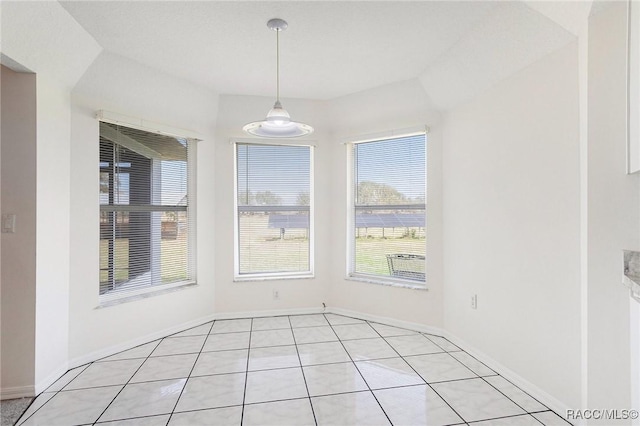 unfurnished dining area with light tile patterned flooring and baseboards