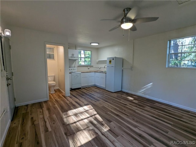 kitchen with stove, white cabinets, white refrigerator, dark hardwood / wood-style floors, and ceiling fan
