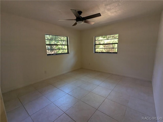 spare room featuring ceiling fan, light tile patterned floors, a healthy amount of sunlight, and a textured ceiling