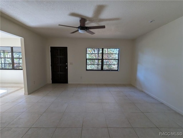 spare room featuring ceiling fan, light tile patterned flooring, plenty of natural light, and a textured ceiling