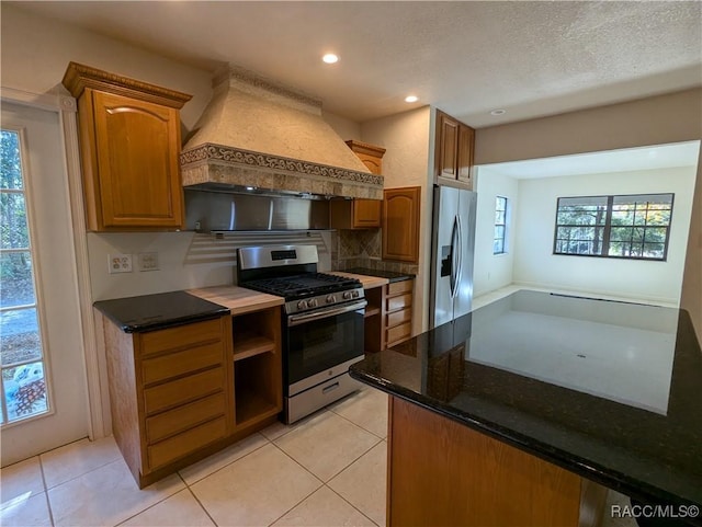 kitchen with premium range hood, light tile patterned floors, a healthy amount of sunlight, and appliances with stainless steel finishes