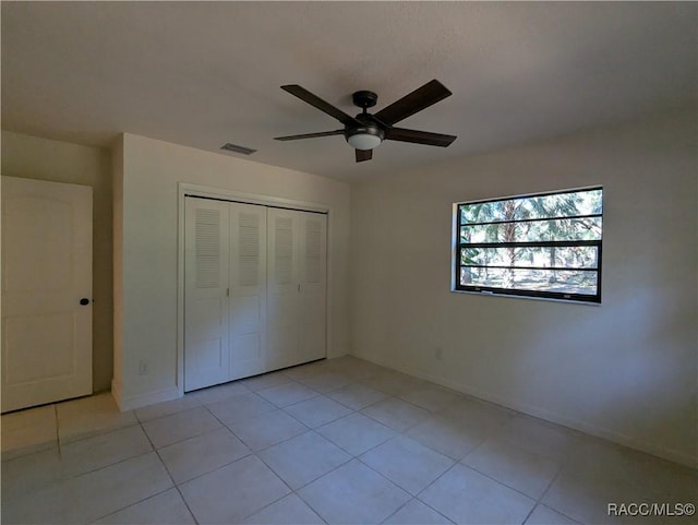 unfurnished bedroom with ceiling fan, light tile patterned floors, and a closet