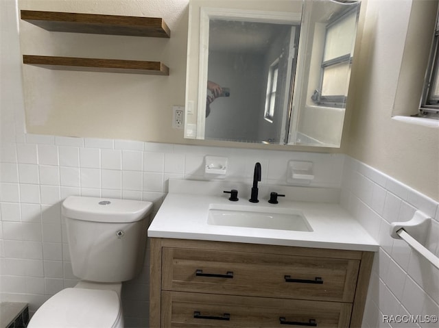 bathroom featuring vanity, toilet, and tile walls