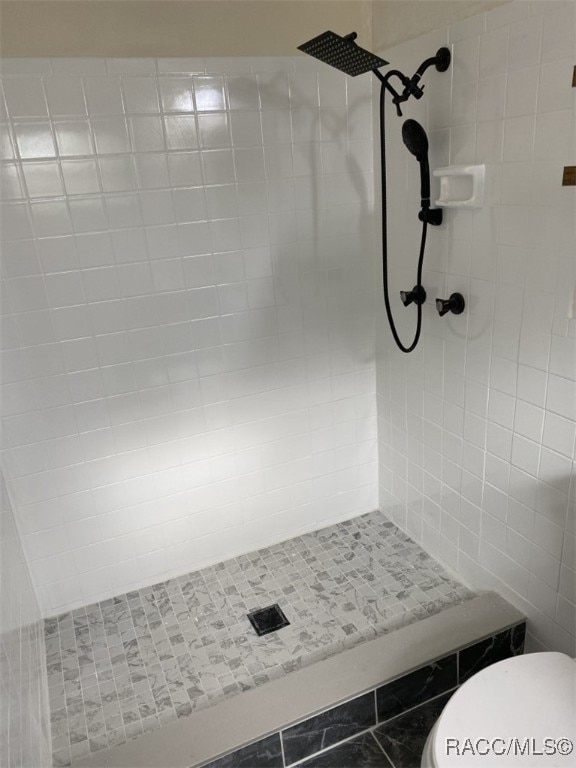 bathroom featuring toilet and a tile shower