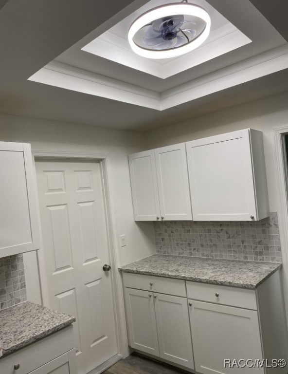 kitchen with a raised ceiling, white cabinetry, and tasteful backsplash