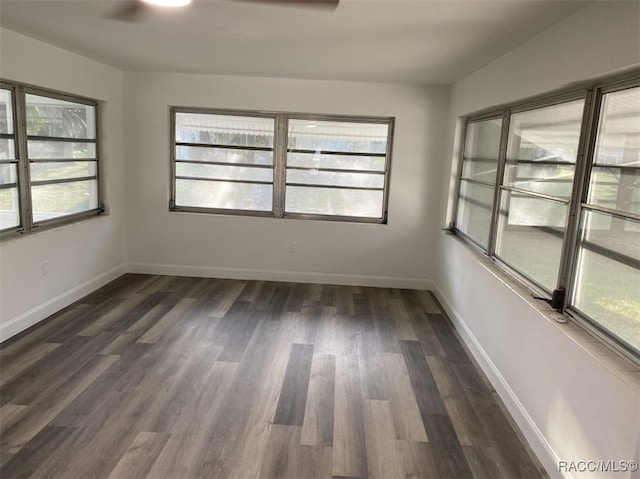 empty room with a wealth of natural light, ceiling fan, and dark wood-type flooring