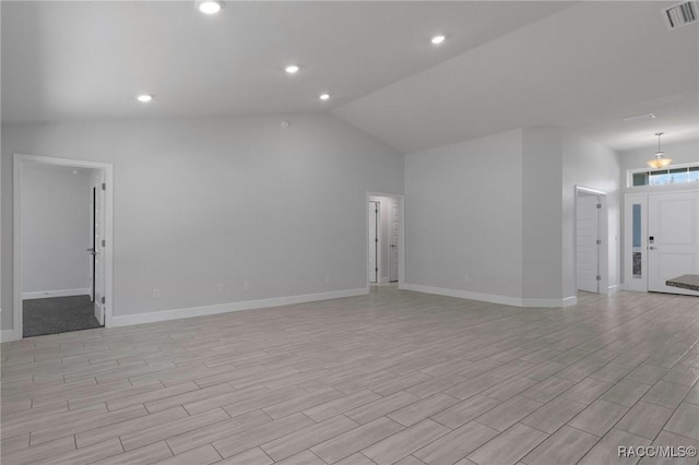 empty room with light wood finished floors, visible vents, baseboards, and vaulted ceiling