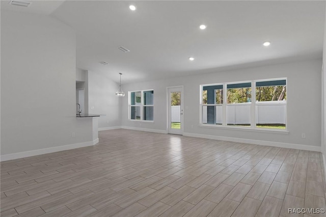 unfurnished living room featuring recessed lighting, baseboards, and lofted ceiling