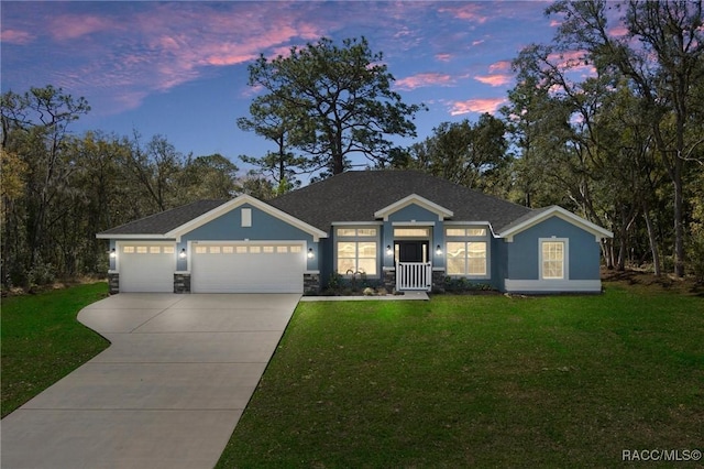 view of front of house featuring driveway, stucco siding, a front lawn, stone siding, and a garage