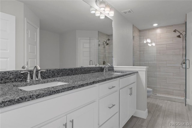 bathroom featuring visible vents, a shower stall, toilet, and a sink