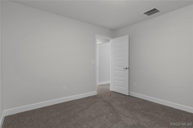 empty room with carpet, visible vents, and baseboards