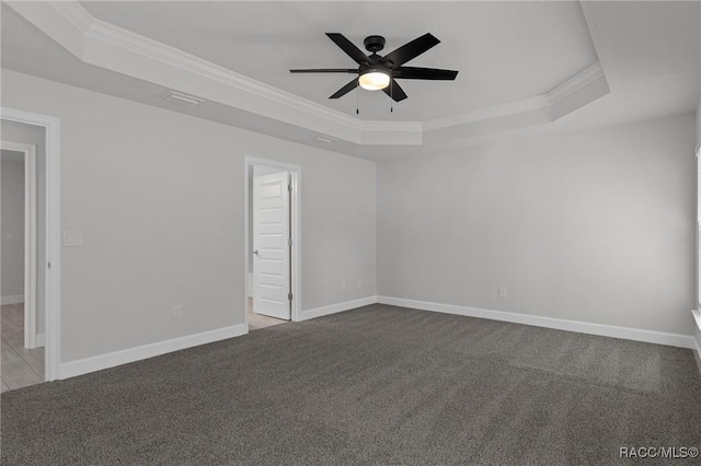 carpeted empty room featuring a tray ceiling, baseboards, a ceiling fan, and crown molding