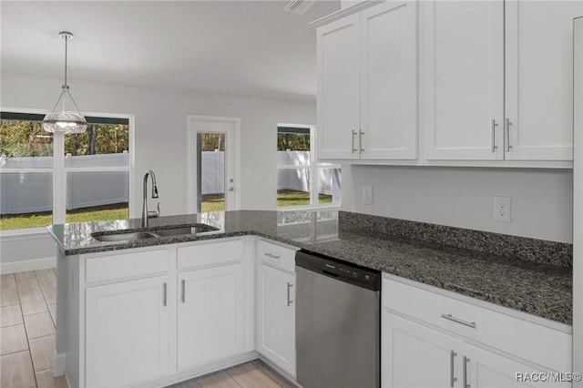 kitchen featuring a sink, dark stone countertops, stainless steel dishwasher, white cabinetry, and a peninsula